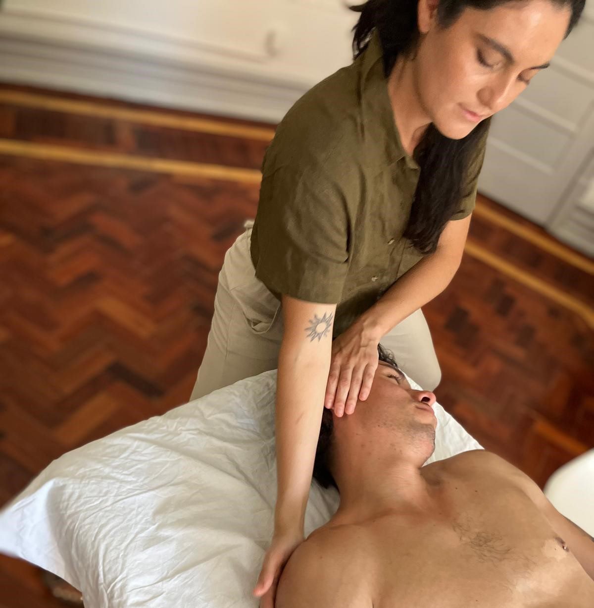 Terapeuta a massajar o pescoço e os ombros de uma pessoa deitada